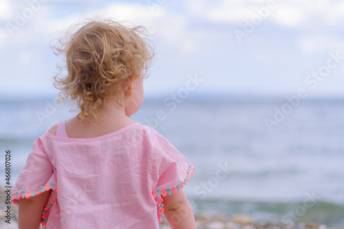 Little girl wear kimono and looking up the ocean or sea at the beach, holiday concept idea with copy space