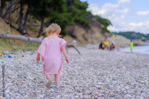 Blonde little girl walking at the beach, kid get angry and turn around her back, holiday concept idea