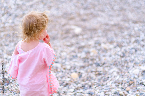 Little girl standing and eat something and  looking for her family  at the beach, holiday concept idea with copy space