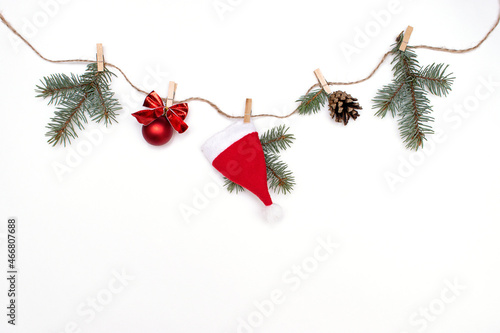 Festive garland of fir branches, red Christmas decorations and Santa Claus hats on a white background.Creative Christmas and New Year background,copy space.