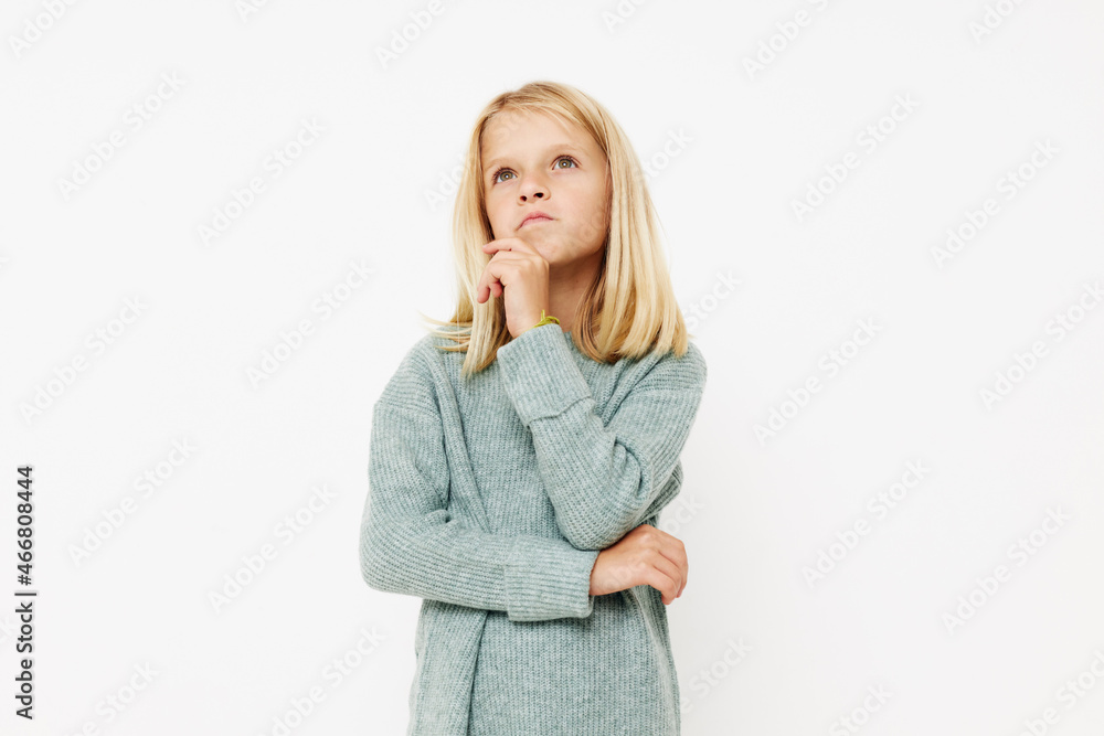 Beautiful little girl in a sweater, grimaces on a light background Beautiful little girl in a sweater, grimaces on a light background