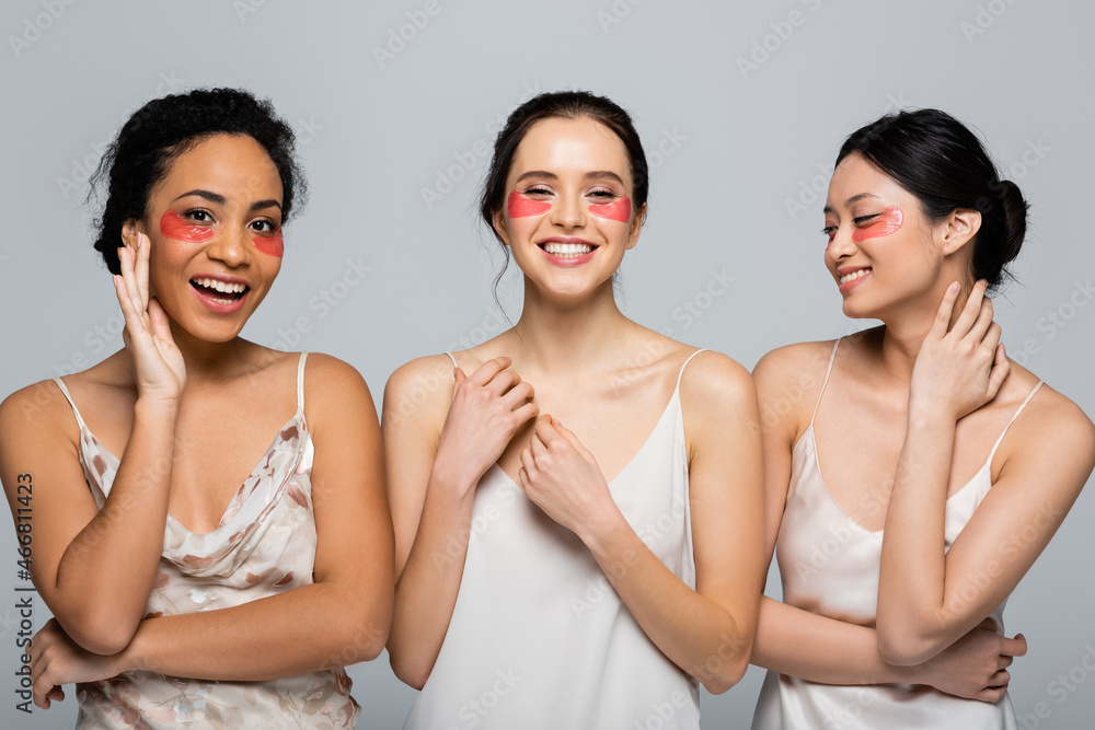 Happy interracial women with eye patches standing isolated on grey Happy interracial women with eye patches standing isolated on grey