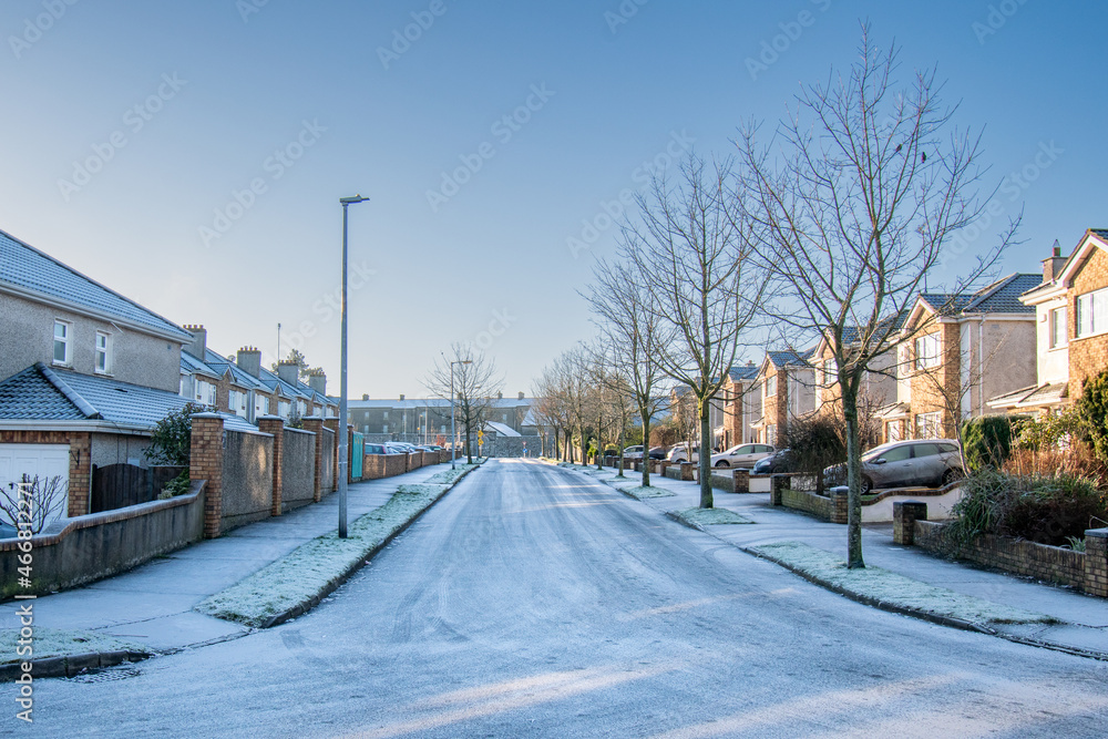Housing estate in winter. Empty road with row of trees after first snow.