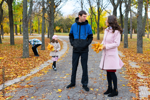 Family resting in the autumn park along the path. Beautiful nature and trees with yellowleaves. photo