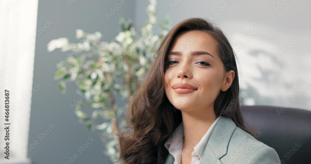 Attractive corporate office worker sits at desk in front of laptop screen looks into camera charmingly smiling flirtatious beautiful secretary corporate head manager with pretty brown hair eyes Attractive corporate office worker sits at desk in front of laptop screen looks into camera charmingly smiling flirtatious beautiful secretary corporate head manager with pretty brown hair eyes