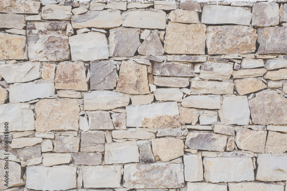 Antique masonry in beige shades. Beautiful textured background from natural stone. Hand laid sandstone or shell rock wall. The concept of reliability, durability, time-tested.