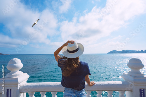 Photography Rear view of woman tourist with sun hat enjoying sea or ocean view