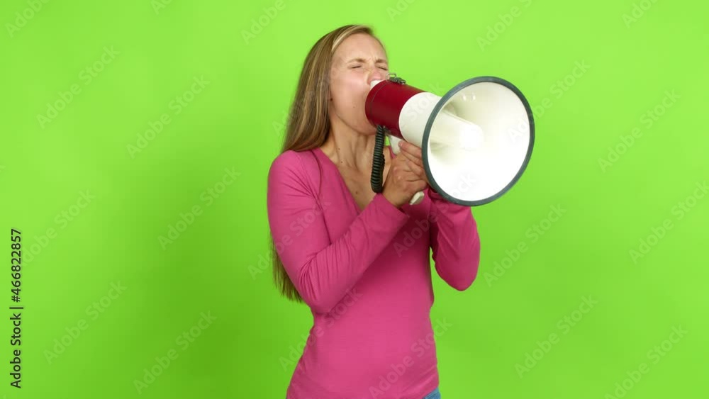 Young blonde girl shouting through a megaphone over isolated background. Green screen chroma key Young blonde girl shouting through a megaphone over isolated background. Green screen chroma key
