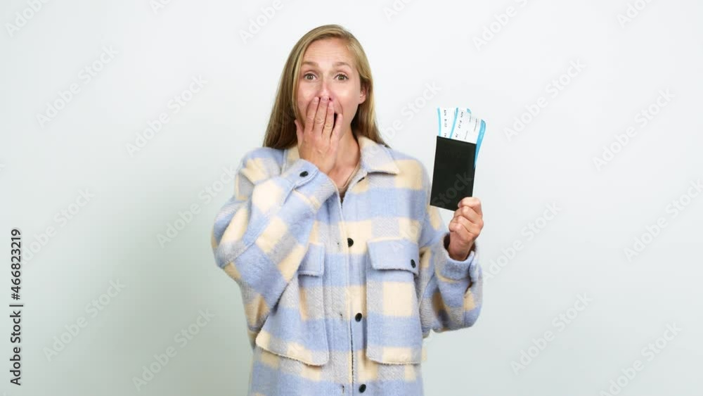 Young blonde girl holding a passport and doing surprise gesture over isolated background Young blonde girl holding a passport and doing surprise gesture over isolated background