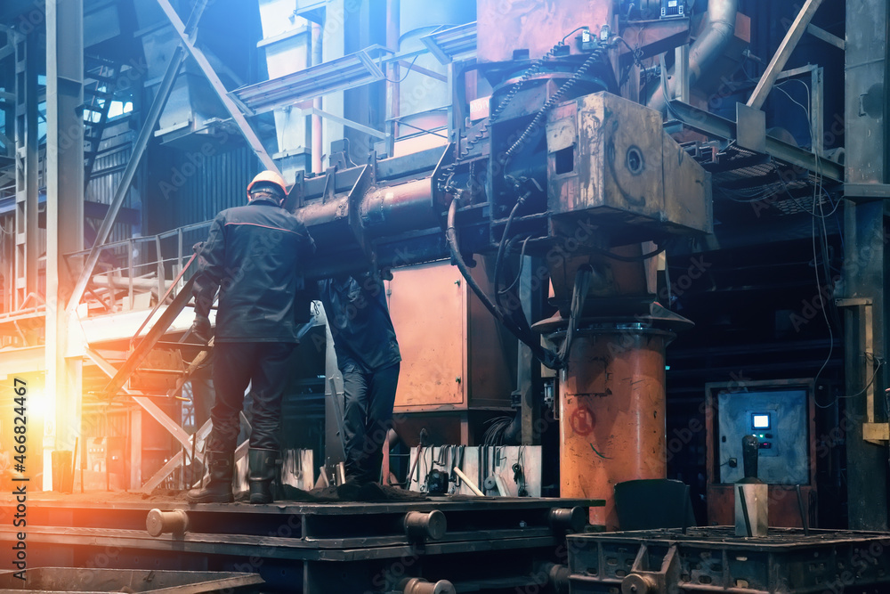 Steel mill interior inside. Workers in workshop of metallurgical plant. Foundry and heavy industry building inside background.