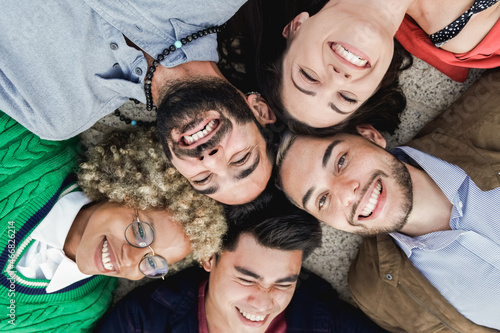 Young multiethnic people lying in circle while having fun outdoor - Focus on right man face