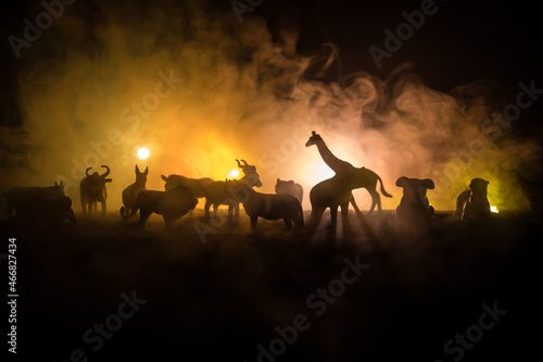 A group of animals are grouped together on a black background with glowing white rays. Animals range from an elephant, zebra, bear and rhino. Use it for a zoo or friends concept.