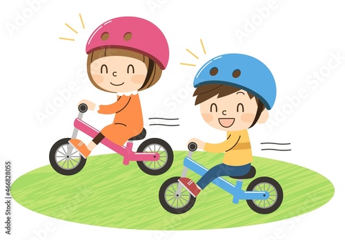 原っぱでキックバイクに乗る2人の子供