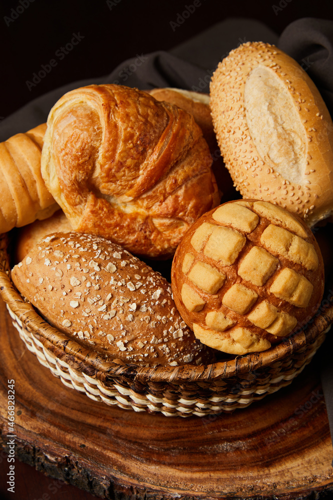 Closeup of breads in a basket on a wooden table. Food and bakery concept. Vertical photo.