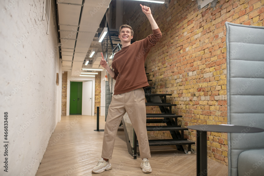 A young man looking happy and enjoyed in the office corridor A young man looking happy and enjoyed in the office corridor
