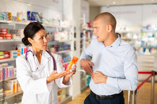 Man complains to a pharmacist about a sore belly. Help in choosing a medicine in a pharmacy