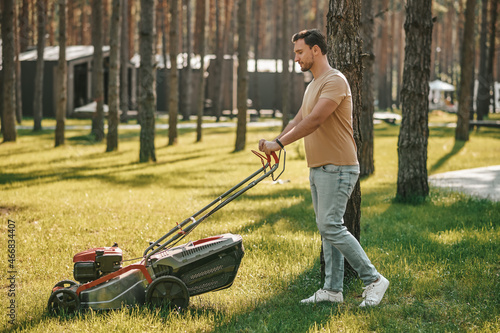 Profile of man with grass-cutter on lawn
