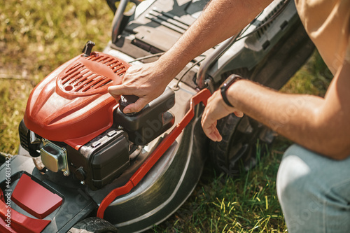 Male hands adjusting lawn mower outdoors