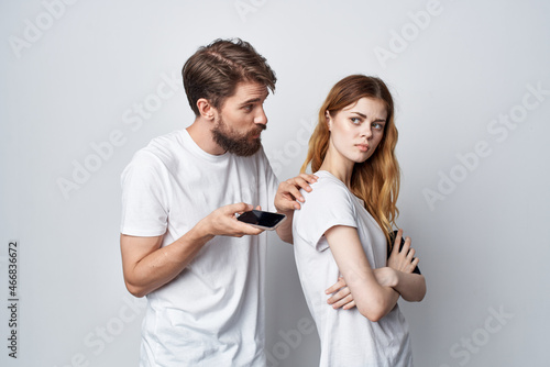 married couple in white T-shirts with phones in their hands studio lifestyle