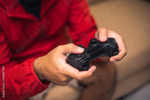 Close up male hands holding joystick game console. Young man playing video game online.