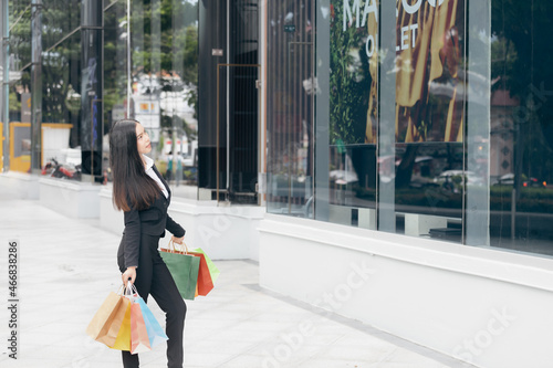 A young woman with shopping bags looking onto the shop window.