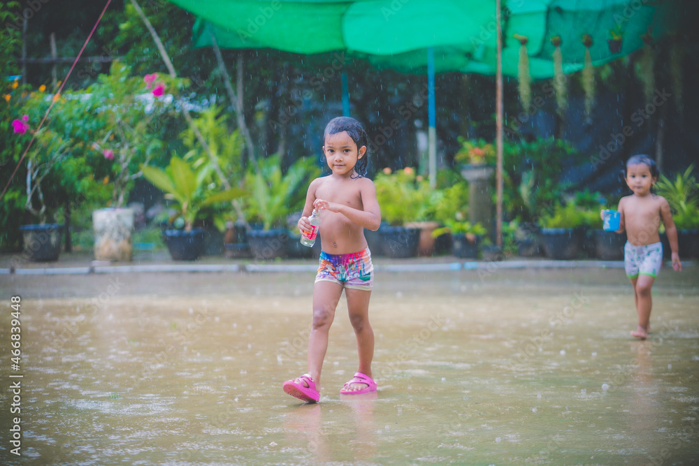 Happy asian little child girl having fun to play with the rain in the evening sunlight Happy asian little child girl having fun to play with the rain in the evening sunlight