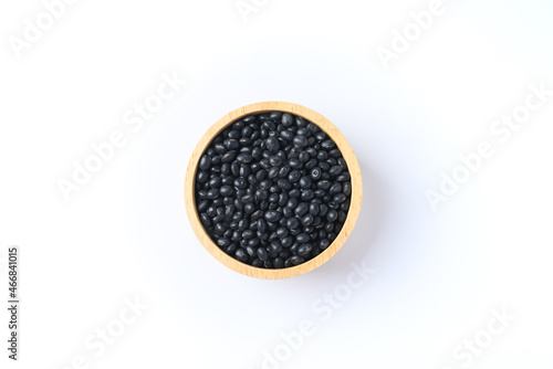 Black soy bean seeds in a wooden bowl on white background