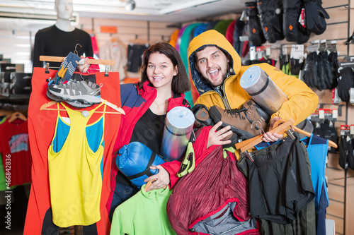 Happy couple demonstration new tourist assortiment in sports clothes store.