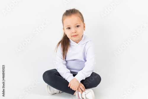 Girl in a white blank hoodie sits on a white background. Kids hoodies mockup.