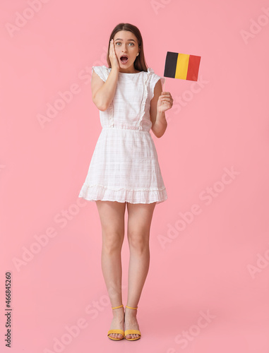Surprised young woman with flag of Belgium on color background