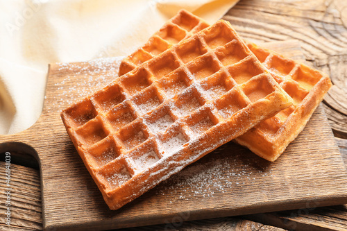 Board with tasty Belgian waffles on wooden background, closeup