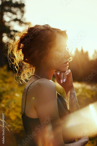Portrait  beautiful woman in forest at sunset. Woman is resting in nature, an art portrait in the rays of the sun