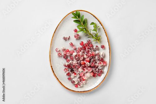 Plate with sugared cranberry on white background