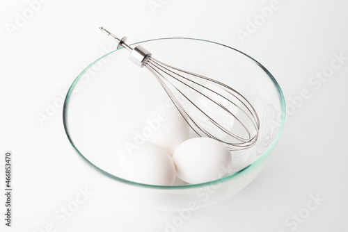 whisk and chicken eggs on white background  
