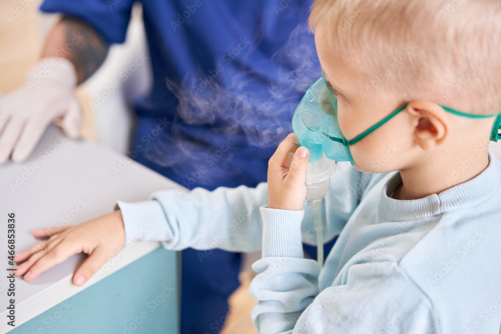 A pediatrician diagnoses lung disease and provides treatment. Breathe the medicine through a nebulizer inhaler.. Portrait of adorable little boy visiting doctor. A pediatrician diagnoses lung disease and provides treatment. Breathe the medicine through a nebulizer inhaler.. Portrait of adorable little boy visiting doctor.