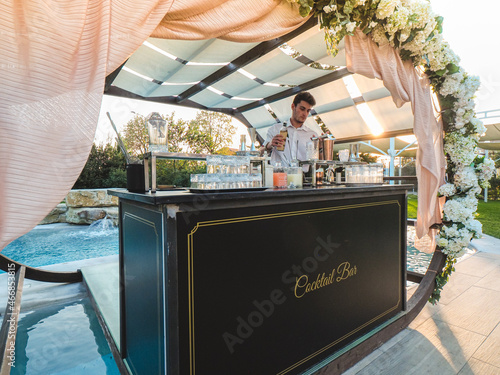 bartender mixing cocktails and drinks outdoor at sunset near a pool in a venue l Fototapet