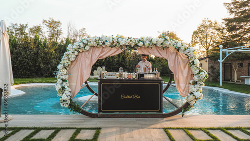 young caucasian bartender at work in a cocktail station outdoors in a location venue in a party at sunset