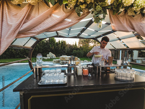 Canvas Print young caucasian bartender at work in a cocktail station outdoors in a location v