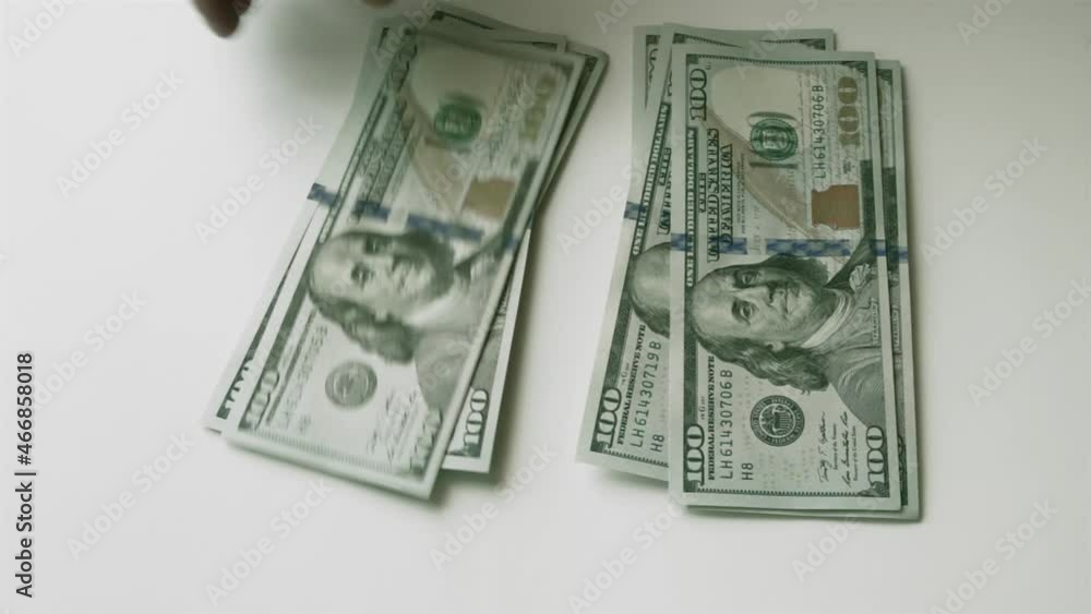 Splitting money into two equal stacks. Men's hand puts hundred-dollar bills on the table, and then takes them away. Fast motion. Splitting money into two equal stacks. Men's hand puts hundred-dollar bills on the table, and then takes them away. Fast motion.