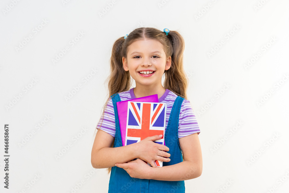 A schoolgirl holds an English textbook in her hands. Learning foreign languages. A schoolgirl holds an English textbook in her hands. Learning foreign languages.