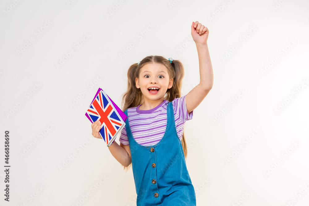 A schoolgirl holds an English textbook in her hand. and raised her hand up. A schoolgirl holds an English textbook in her hand. and raised her hand up.