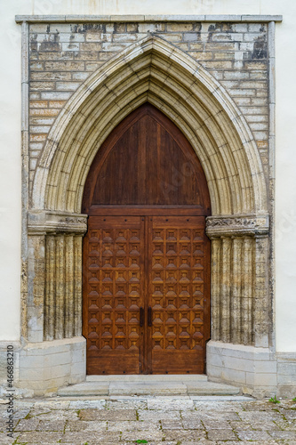 Ancient wooden door in a stone arch with also stone facade.