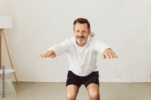 Fotografie Middle-aged man exercising doing squats with arm stretch