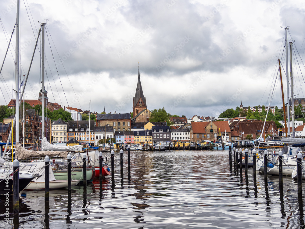 Fototapeta premium Sail boats in the port of Flensburg, St. Jorgen's Church in the background. Schleswig-Holstein in Germany