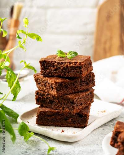 Chocolate brownie pie slices in a white plate on a light background. Homemade blondie bars traditional American dessert closeup