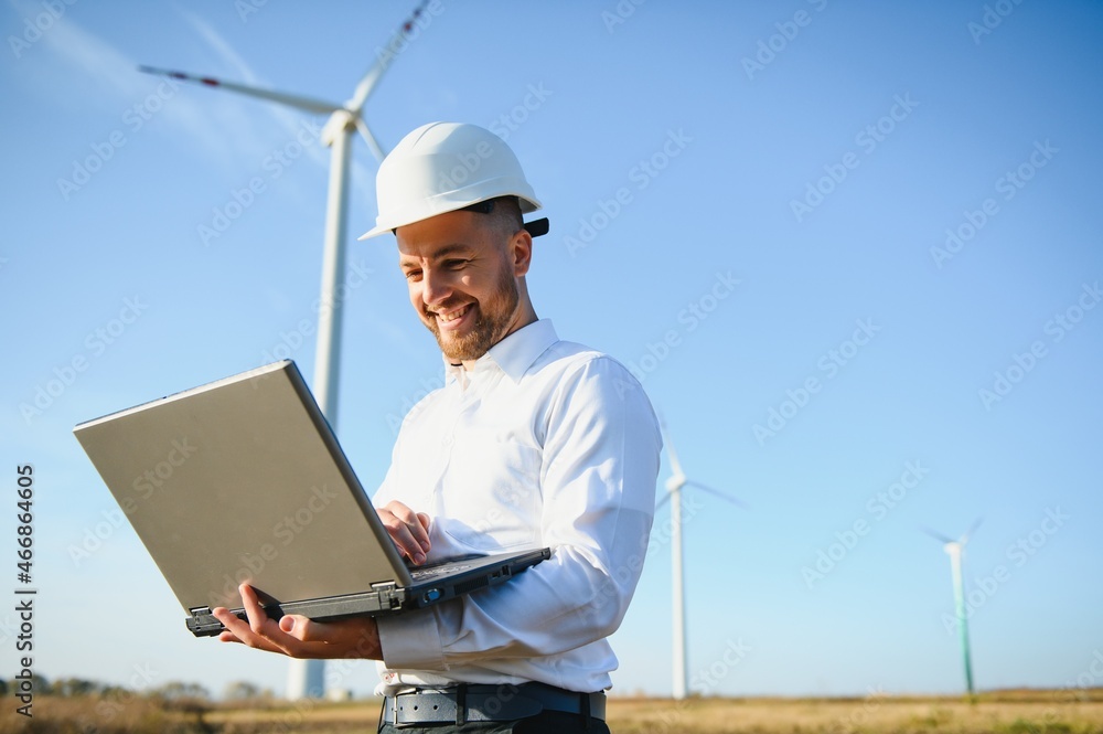 Young engineer man looking and checking wind turbines at field Young engineer man looking and checking wind turbines at field