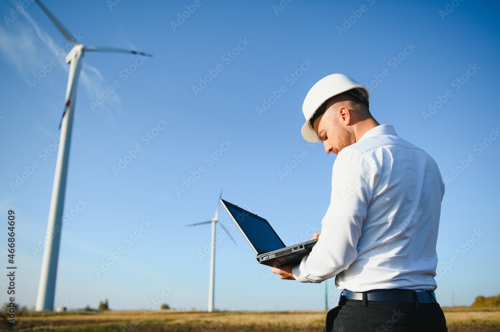 Engineer standing and hoding laptop with wind turbine. Engineer standing and hoding laptop with wind turbine.