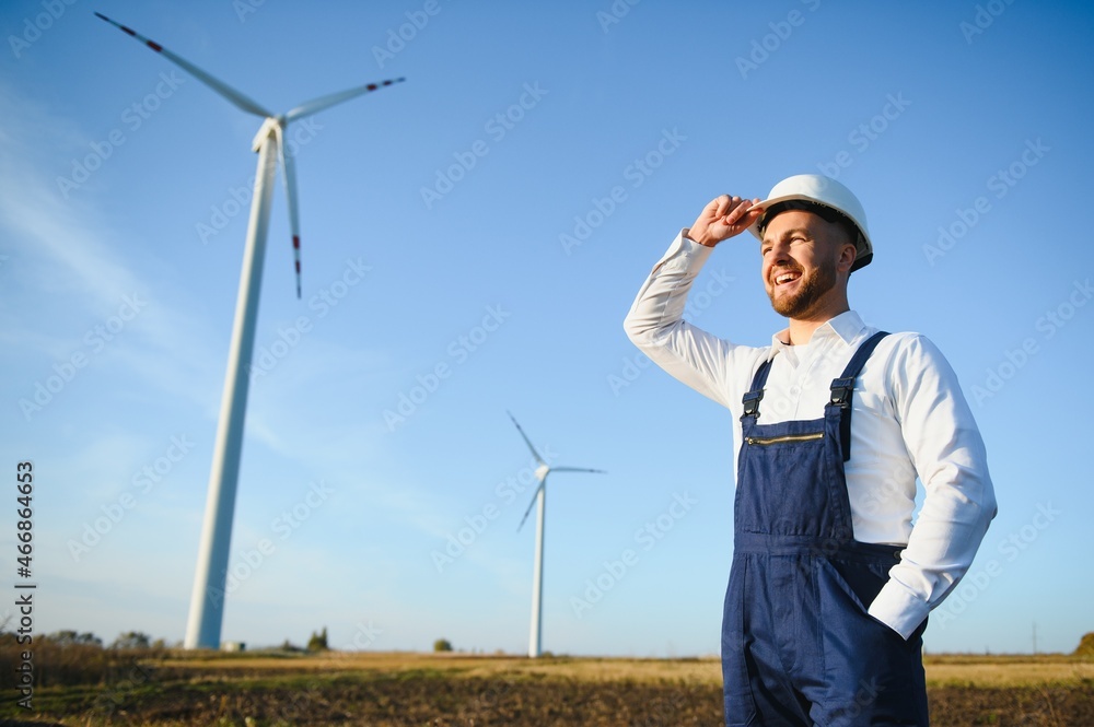 Engineer is checking energy production on wind turbine. Worker in windmills park in helmet. Engineer is checking energy production on wind turbine. Worker in windmills park in helmet.