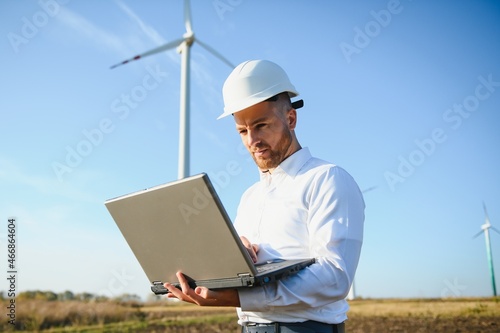 Young engineer man looking and checking wind turbines at field