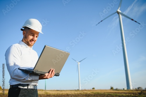 Engineer standing and hoding laptop with wind turbine.